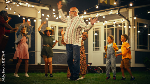 Active and Healthy Senior Man Dancing Together with Family and Friends at an Evening Garden Party Celebration. Young and Elderly People Having Fun on a Warm Summer Night.
