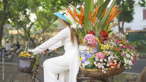 Portrait of Asian peddler with bike and flowers, Vietnamese woman girl traveling in Hanoi urban city town, Vietnam. People lifestyle.