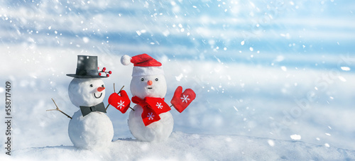 Christmas winter banner with a couple of snowmen on the background of snow in the winter forest. Holiday background with copy space for text