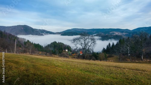 The fog is moving in the mountain valley above the lake. Cloudy morning in the mountains. Timelapse with a view of the village houses, lake and mountains. Tara, Serbia. High quality 4k footage