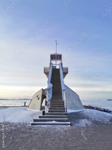 Lighthouse and observation deck on the pier on the coast of Gulf of Bothnia of the Baltic sea in winter day. Nallikari beach, Oulu, Finland. photo