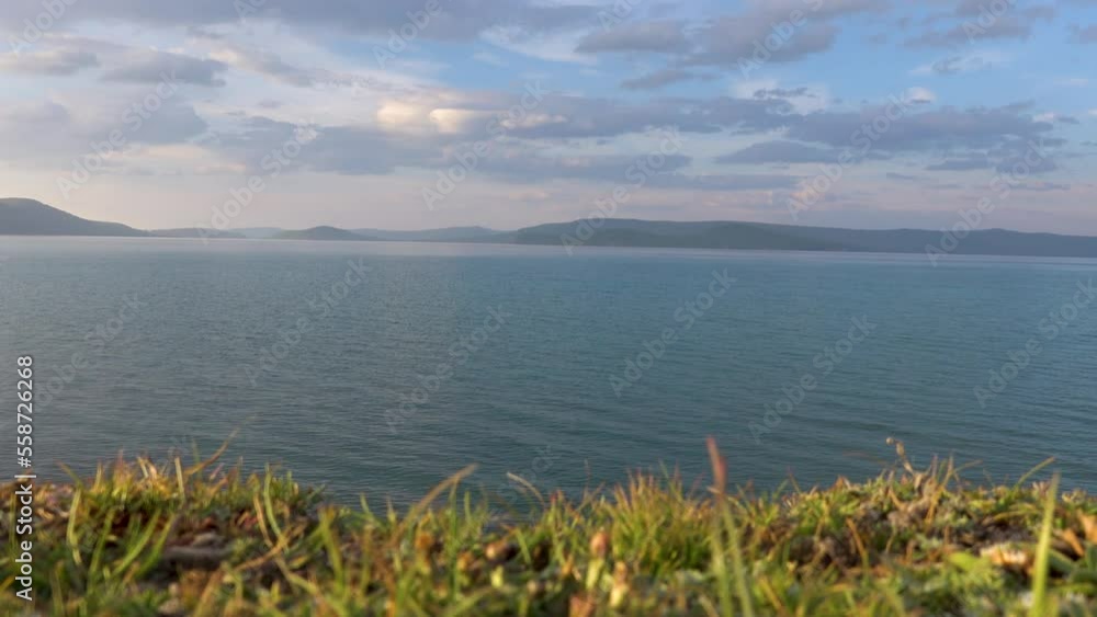 Majestic view of lake Khovsgol with beautiful mountains in the background. Blue water edge with the misty looking sky in the horizon. Majestic view of lake Khovsgol with beautiful mountains in the background. Blue water edge with the misty looking sky in the horizon.