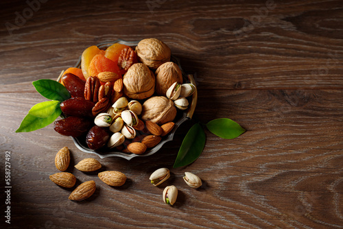 Mix of dry fruits and nuts on a wooden table, dark background leaves. Concept of the Jewish holiday. Top view