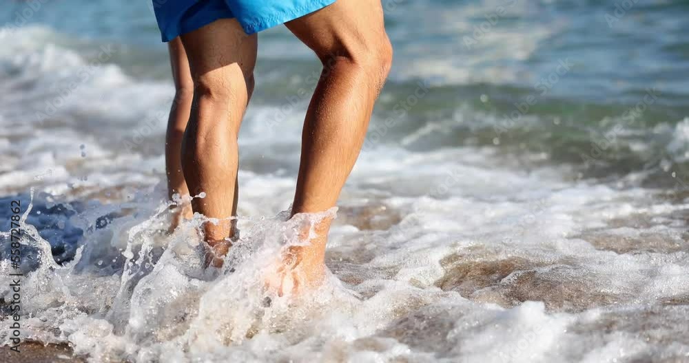 Couple stands on sand and waves splash feet Couple stands on sand and waves splash feet