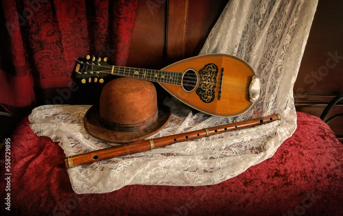 Still life of mandolin and flute and bowler hat on lace and velvet background