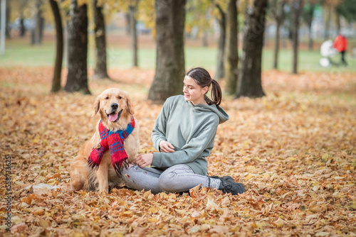 Young beautiful dark-haired girl plays with a golden retriever in the park.