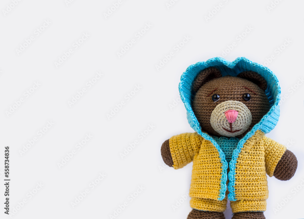 Knitted bear on a white background in a yellow and blue suit. Space for text Knitted bear on a white background in a yellow and blue suit. Space for text