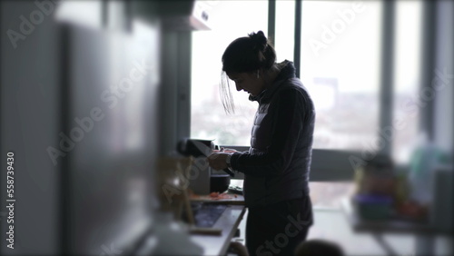 Candid mother cooking and taking care of baby at the same time, mom multi-tasking