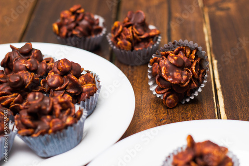 Chocolate cornflake cookies served on white plates. Chocolate cornflake cake in blue paper cupcake case