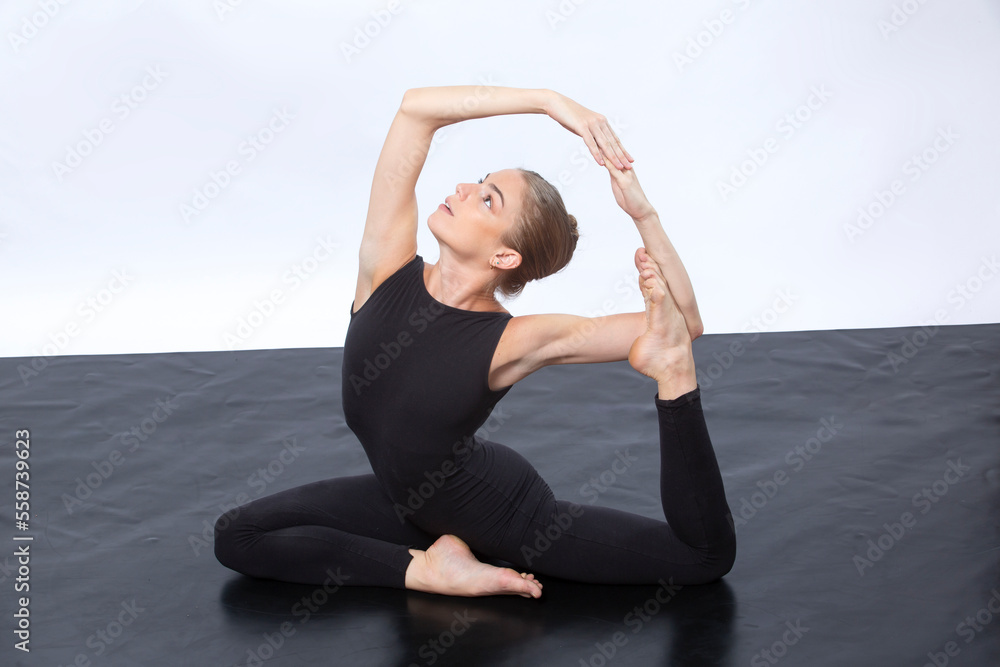 Young woman in black onsie in mermaid yoga pose.