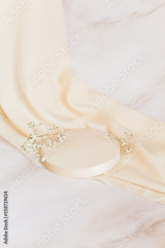 Empty wooden podium light background. Product presentation with flowers, silk cloth and leaves