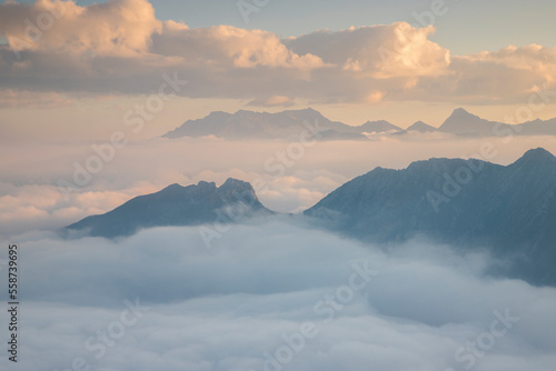the Peaks of the mountains in the Adamello park emerge from the clouds at dawn, from Pizzo Badile Camuno peak, Valle Camonica, Lombardy, Italy. © Andrea
