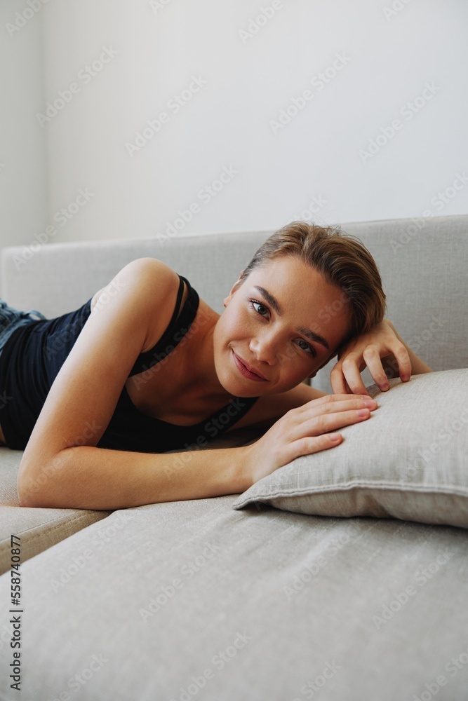 Young woman with short haircut hair having fun at home on the couch smile and happiness, vacation at home, natural posing without filters, free copy space Young woman with short haircut hair having fun at home on the couch smile and happiness, vacation at home, natural posing without filters, free copy space