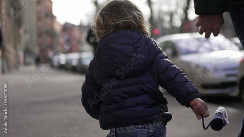 Baby toddler running in sidewalk during winter outside. Infant sprinting in city