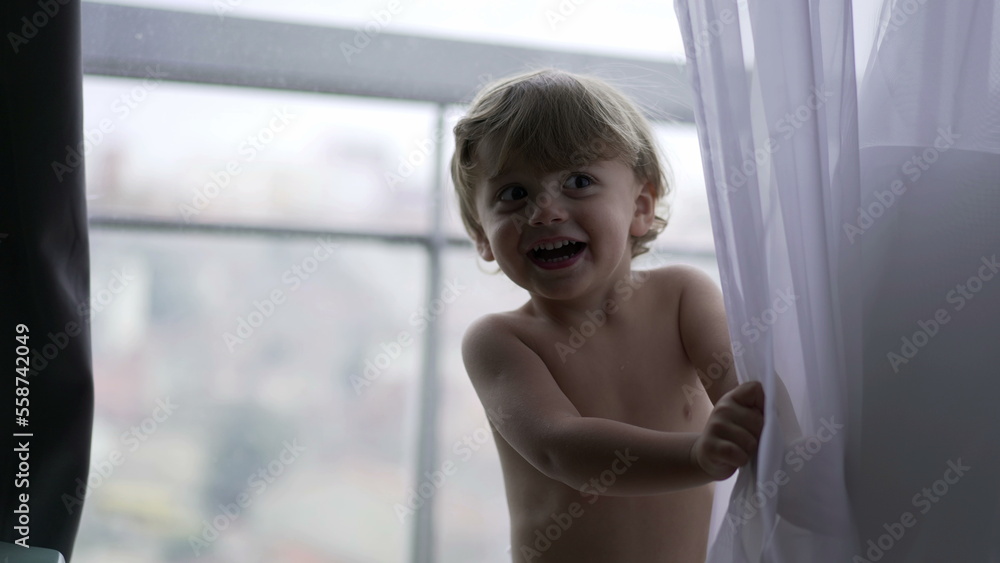 Baby toddler boy hiding behind curtains3