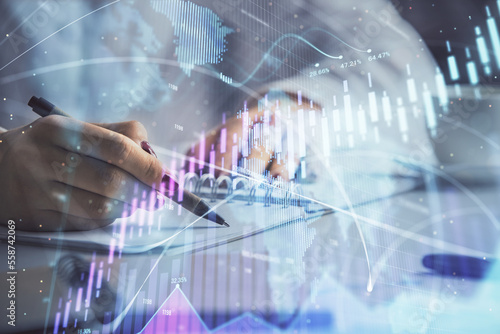 Double exposure of woman s hands making notes with forex graph hologram. Concept technical analysis.