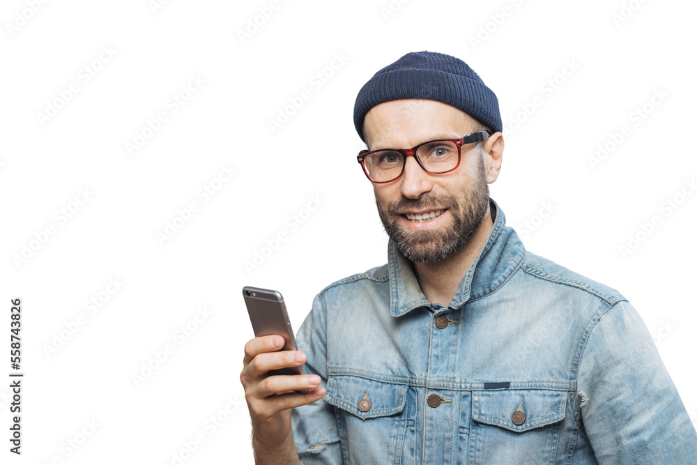 Stusio shot of happy bearded man with stubble holds modern smart phone in hands, enjoys online communication, connected to wireless internet, isolated over white background. Communication concept