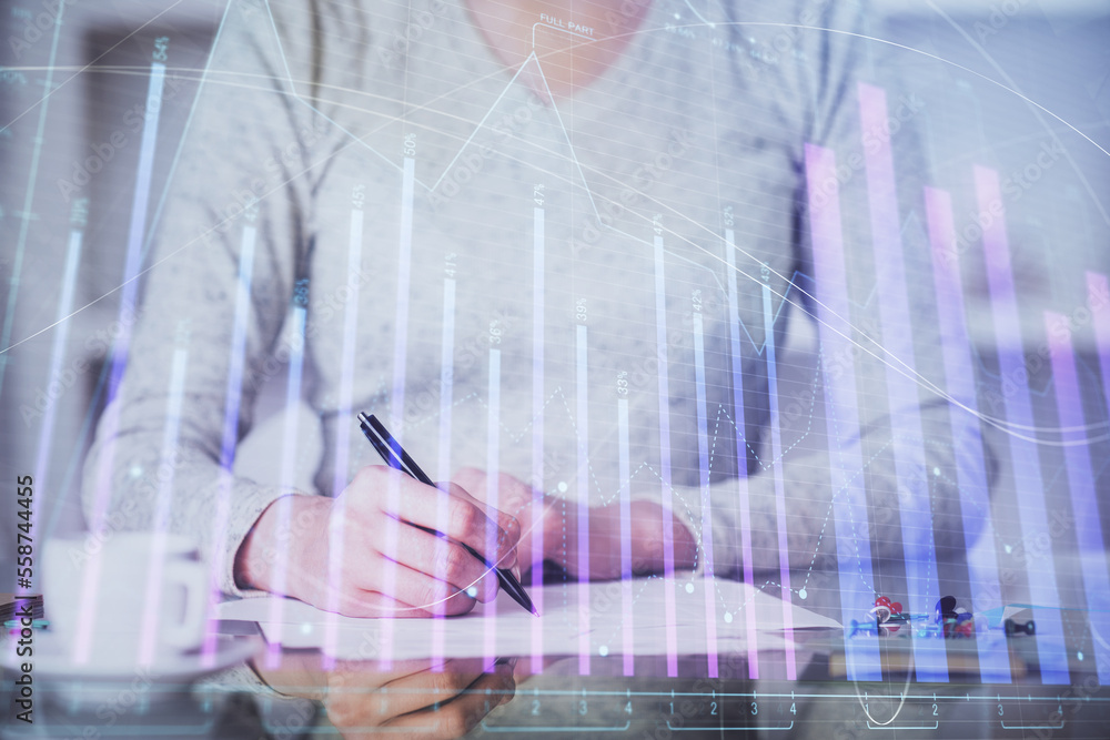 Hand taking notes in notepad. Forex chart holograms in front. Concept of research. Multi exposure Hand taking notes in notepad. Forex chart holograms in front. Concept of research. Multi exposure