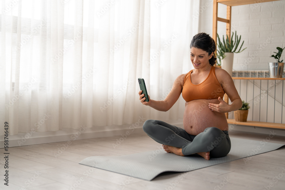 Pregnant fitness young woman having a break from exercising and using mobile phone. Pregnant fitness young woman having a break from exercising and using mobile phone.
