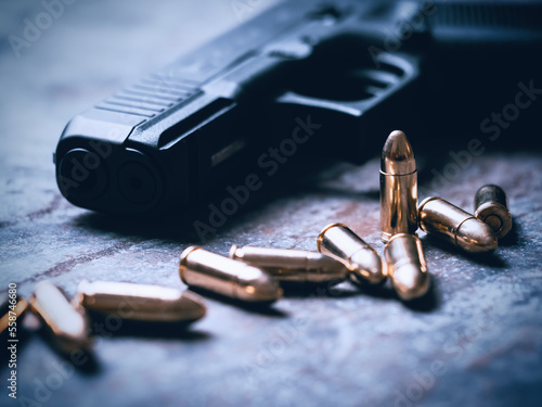 Fotografia Hand gun with ammunition on dark background