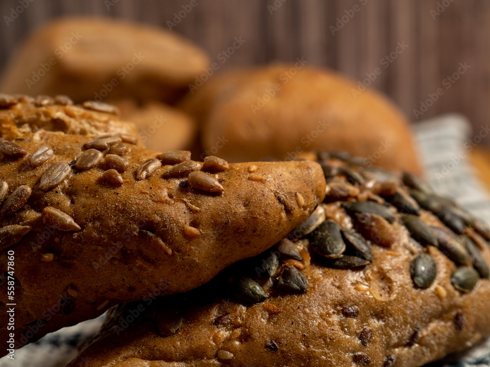 Naklejka premium Dark buns on a wooden background. Bakery products with grains.