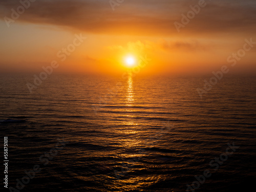 A Sunset with a mild clouded Sky over a calm sea  with the sun framed in the middle. Porto Dinheiro - Lourinha - Portugal 