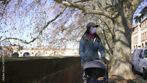 Mother walking outside with stroller while wearing covid face mask2 photo