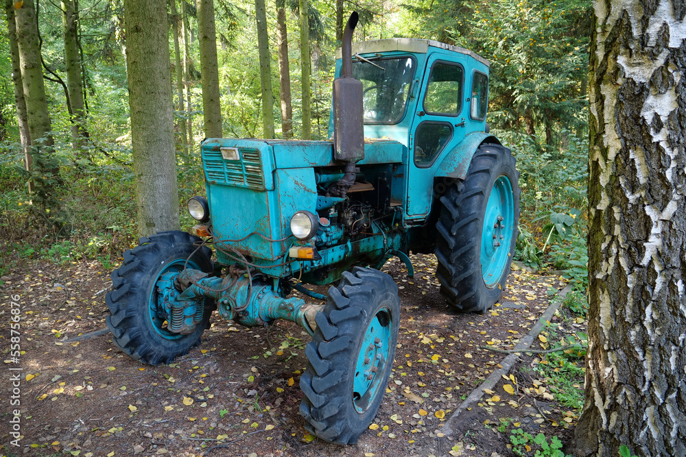 Blue tractor stands in the forest Blue tractor stands in the forest