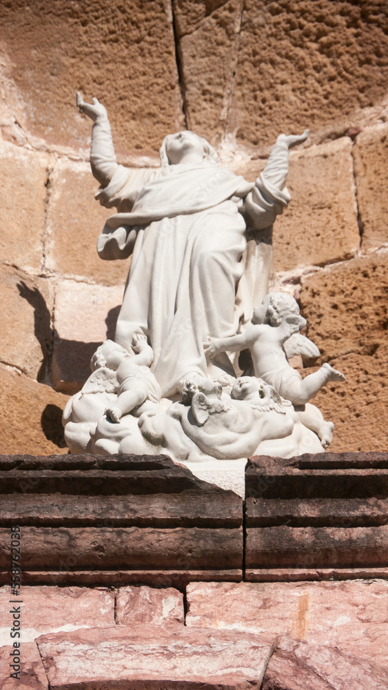 Fototapeta premium Escultura en fachada de pequeña iglesia rural de piedra rosada