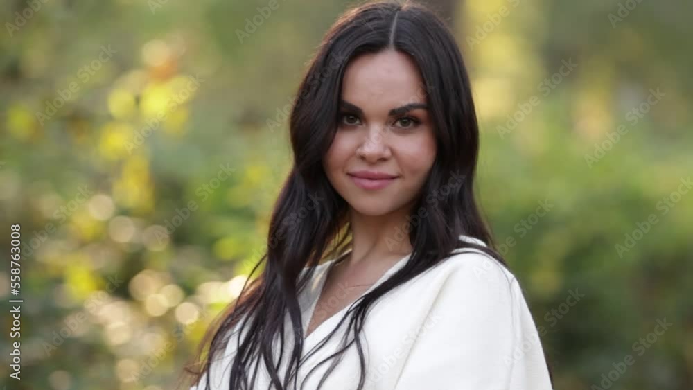 Portrait of attractive smiling caucasian brunette woman is looking in camera. The face of a happy and relaxing beautiful woman with long hair outdoor. Looking Happy, feeling liberty. Ukrainian Girl Portrait of attractive smiling caucasian brunette woman is looking in camera. The face of a happy and relaxing beautiful woman with long hair outdoor. Looking Happy, feeling liberty. Ukrainian Girl