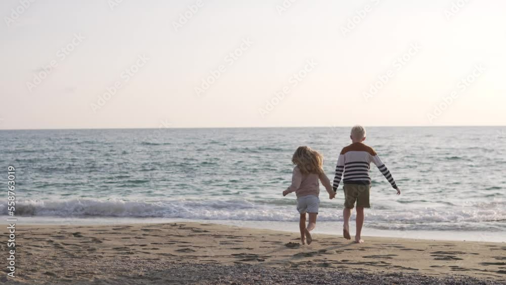 A boy and a little girl run to the sea on the beach holding hands. A boy and a little girl run to the sea on the beach holding hands.