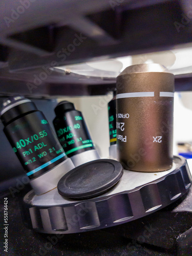 Foto Objective lens turret of inverted microscope in research institute, contains four objective lenses with different magnifications