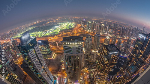 Panorama of Dubai Marina with JLT skyscrapers and golf course day to night timelapse, Dubai, United Arab Emirates.