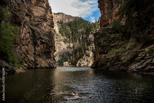 women swimming in bikini in river in canyon in Colorado with sky