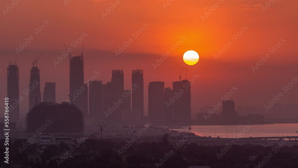Sunrise over Dubai Creek Harbor with skyscrapers and towers under construction aerial timelapse