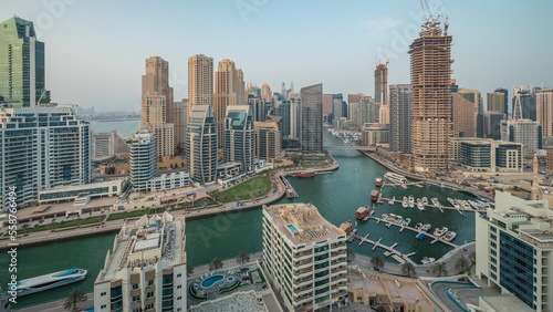 Panorama showing Dubai Marina with several boat and yachts parked in harbor and skyscrapers around canal aerial timelapse. © neiezhmakov