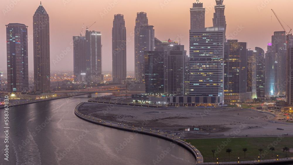Cityscape of skyscrapers in Dubai Business Bay with water canal aerial day to night timelapse