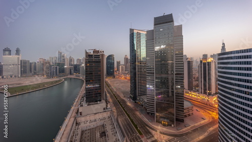 Cityscape of skyscrapers in Dubai Business Bay with water canal aerial night to day timelapse