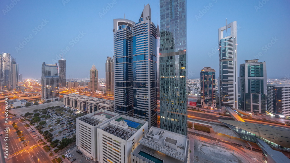 Aerial view of Dubai International Financial District with many skyscrapers night to day timelapse.