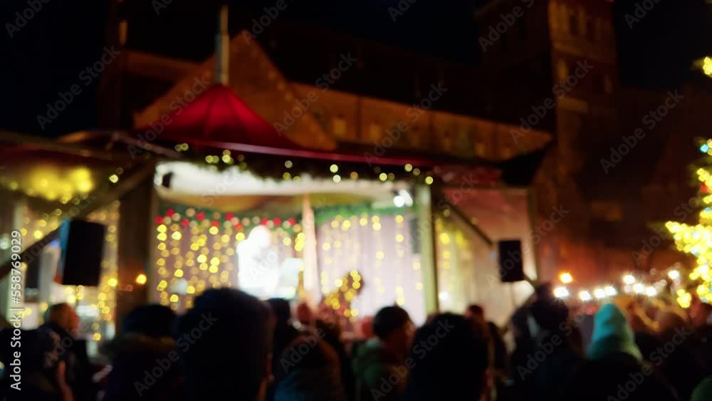 Defocused: Group of people dancing at a DJ performance outdoors before Christmas at night Defocused: Group of people dancing at a DJ performance outdoors before Christmas at night