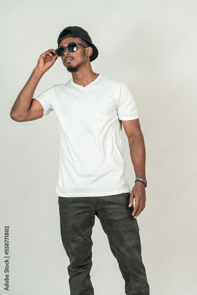 A young handsome man wearing white blank shirt and a glasses, doing a simple pose with on of his hand on his glasses A young handsome man wearing white blank shirt and a glasses, doing a simple pose with on of his hand on his glasses