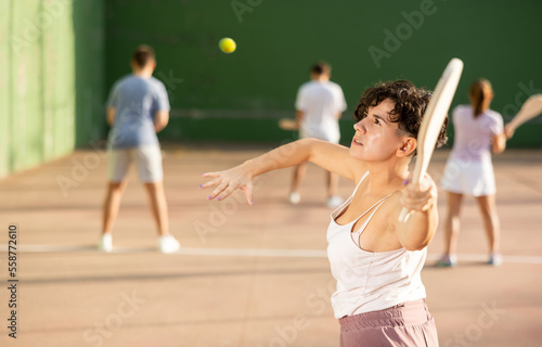 Active womans with enthusiasm playing paleta fronton group on the outdoor court © JackF
