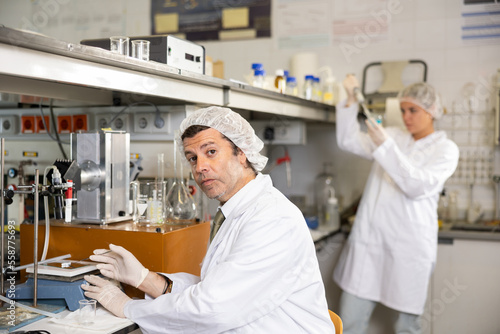 Adult male scientist chemist concentratedly weighs the capsules on the scales in the laboratory