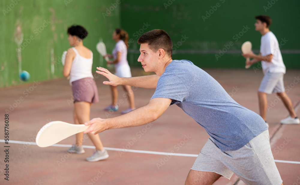 Caucasian young man serving ball with special equipment, wooden paleta
