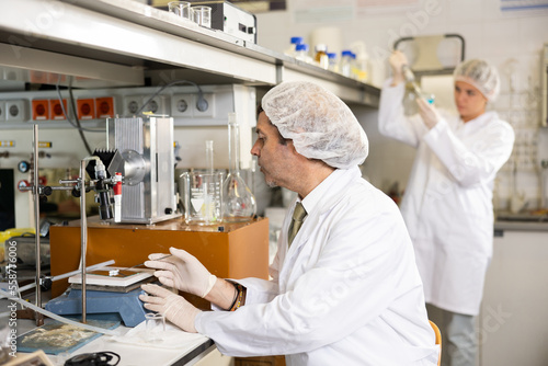 Adult male scientist chemist concentratedly weighs the capsules on the scales in the laboratory