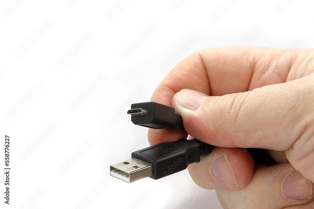 A hand holds a cable with USB connectors of different types. Isolated on white background. A hand holds a cable with USB connectors of different types. Isolated on white background.