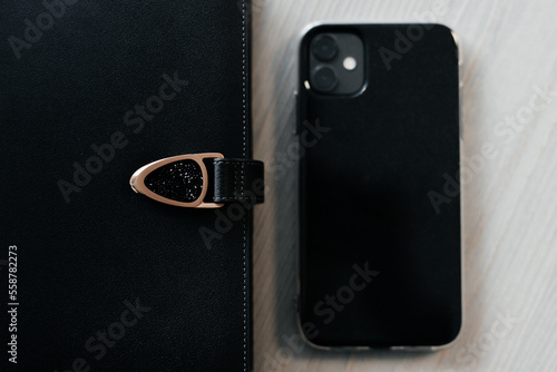 concept of leather black diary and smartphone on the table