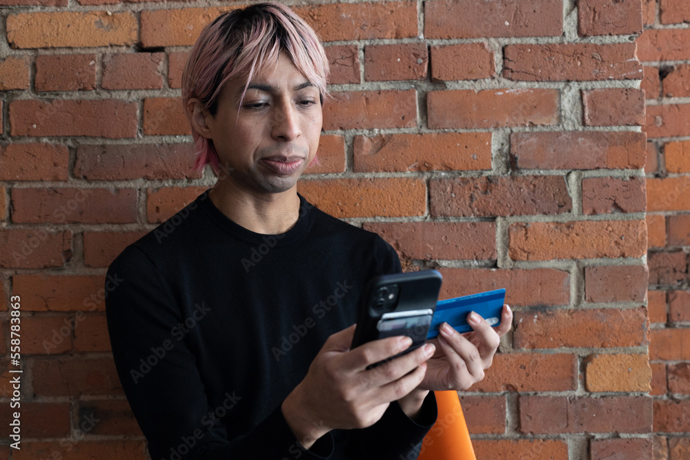 Fototapeta premium Non-binary person using their phone outside.