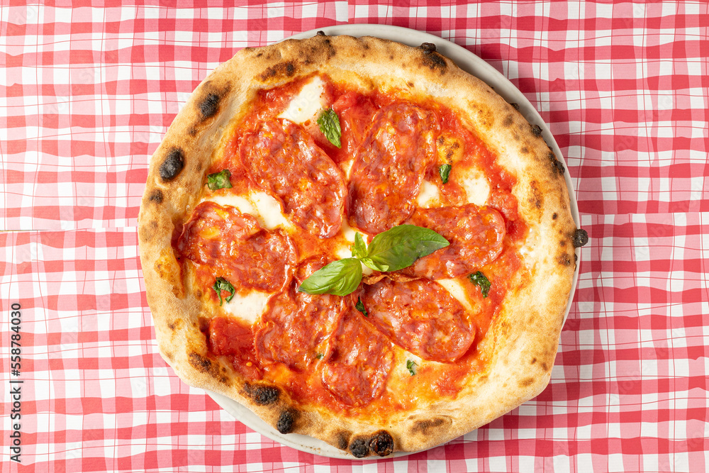 View from above of delicious salami, ham and cheese pizza on a checkered tablecloth. High quality photo View from above of delicious salami, ham and cheese pizza on a checkered tablecloth. High quality photo