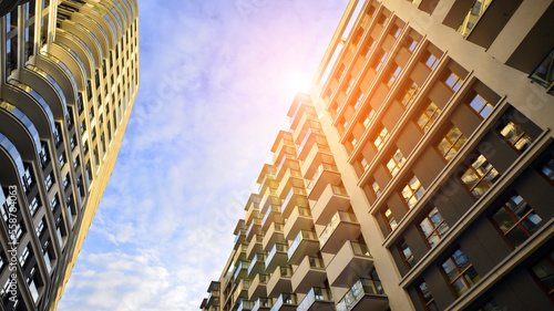 The narrow passage between modern residential buildings. Walls of high-rise apartment buildings and a narrow strip of sky between them. Modern urban living districts. Bottom view.

